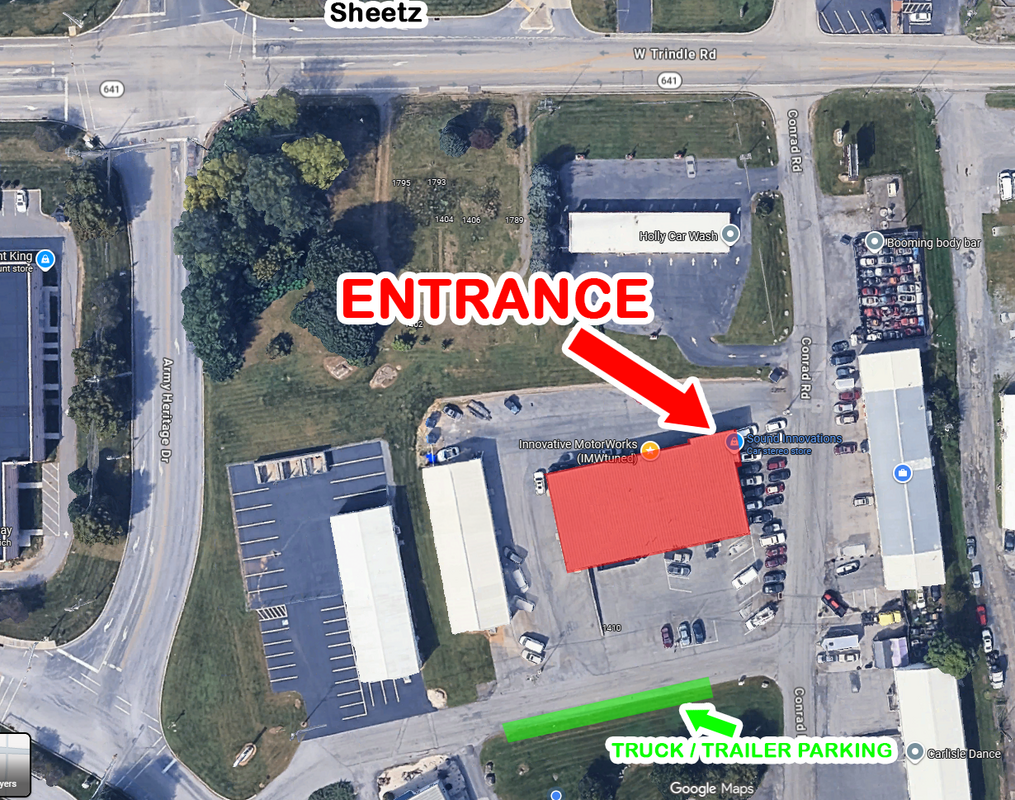 Overhead map: entrance on the north side of the red-roof building; truck and trailer parking highlighted green along the south driveway